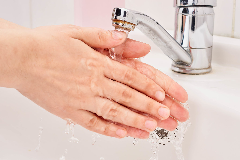 A female washing her hands under warm water