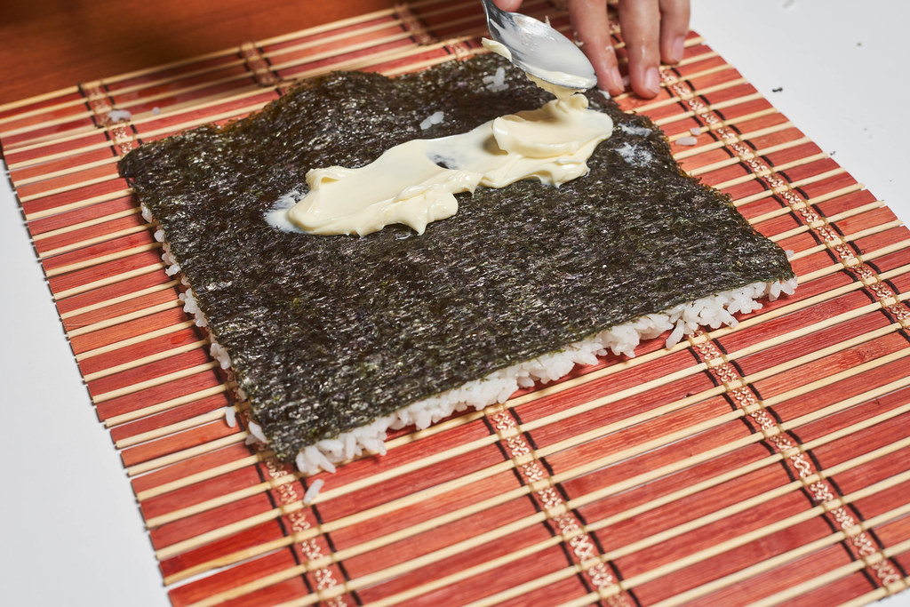 A female with spoon putting cheese cream on nori seaweed sheet