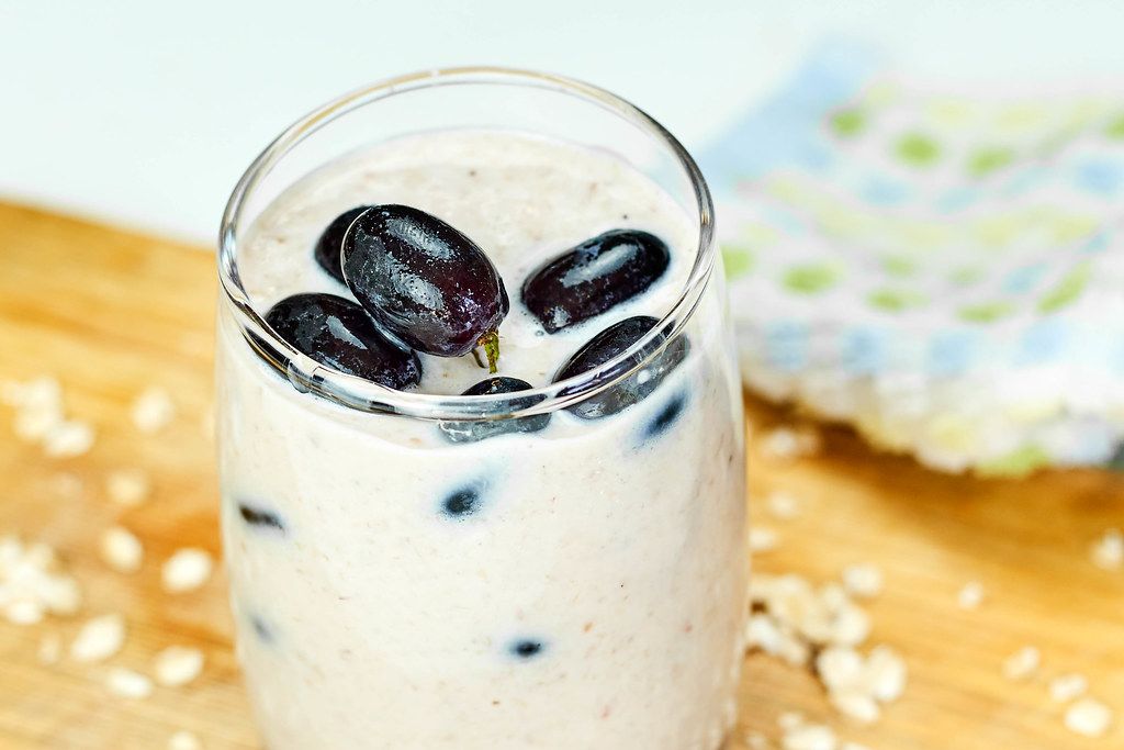 A glass of banana smoothie with grapes