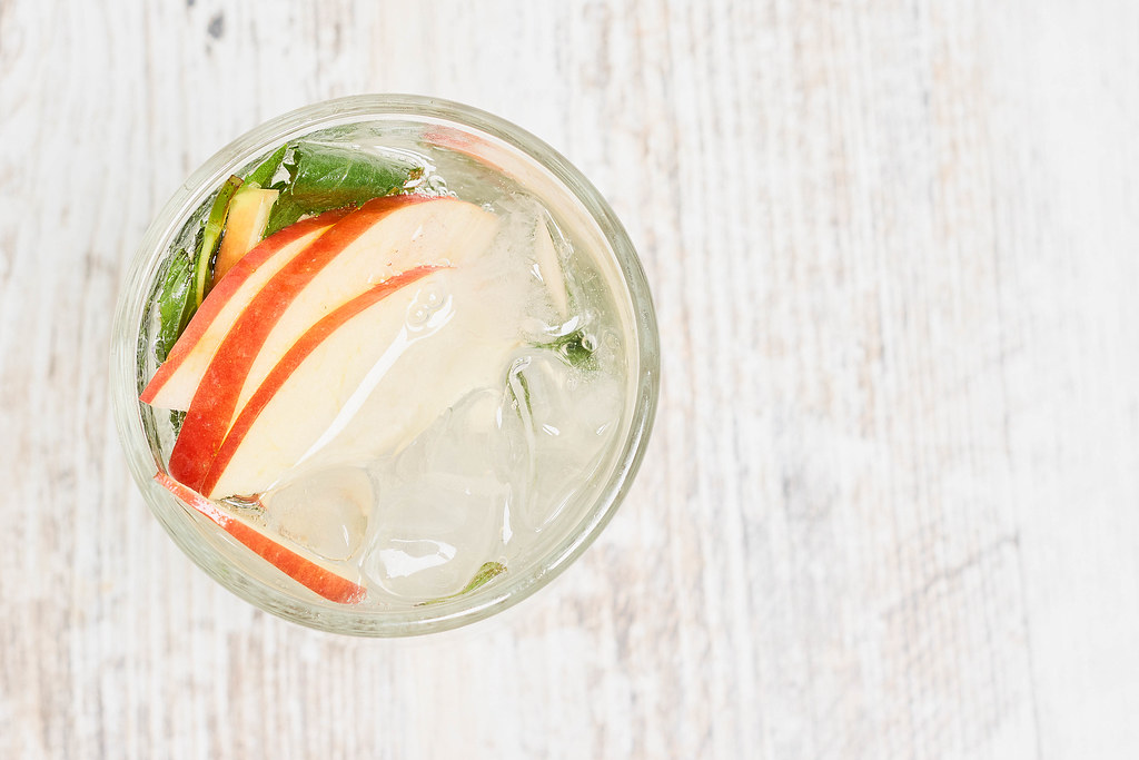 A glass of soft cooling summer drink with apple slices and mint leaves