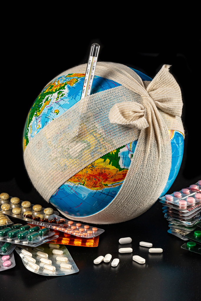 A globe in a bandage, with a thermometer and pills - the concept of global diseases and pandemics