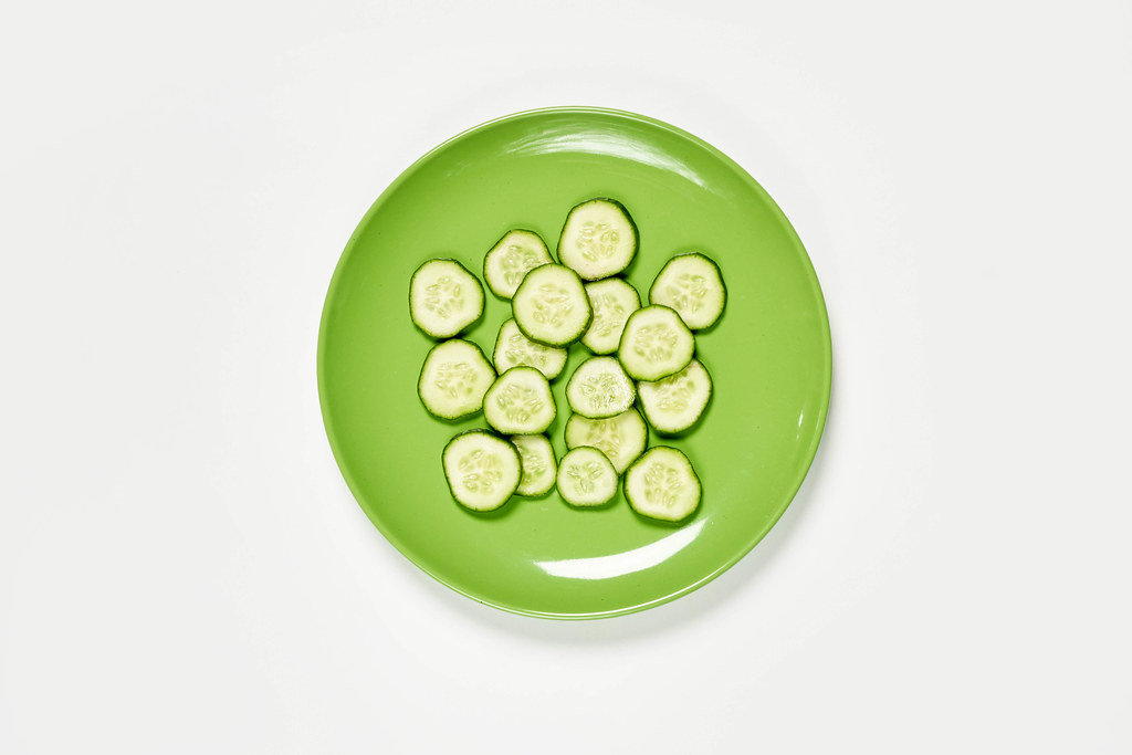 A green plate full of cucumber slices