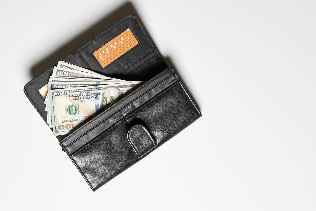 A leather wallet with a pile of us dollar banknotes
