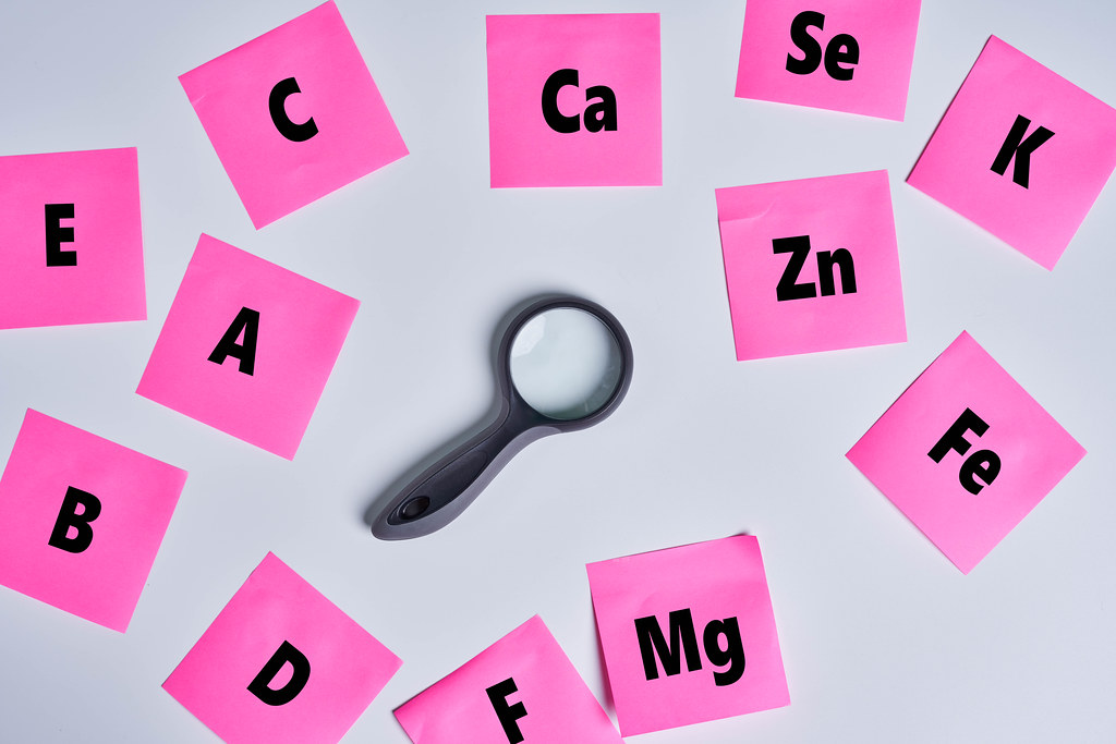 A magnifying glass among sticky notes with various vitamins