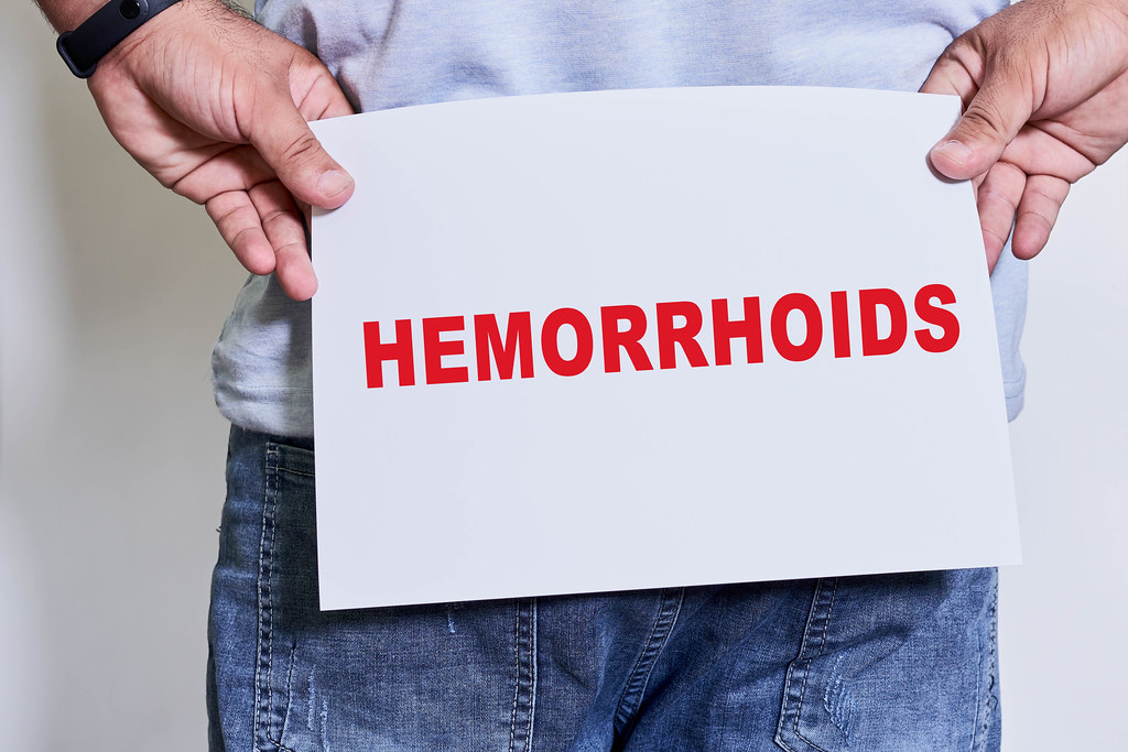 A male holding paper card with Hemorrhoids text