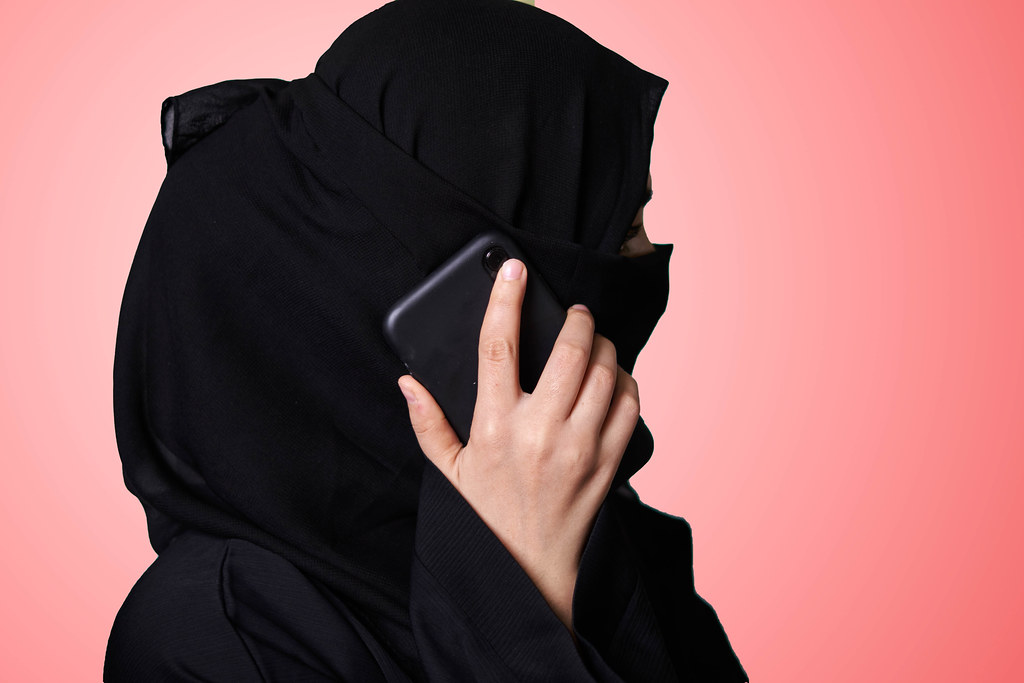 A muslim woman in hijab talking on phone