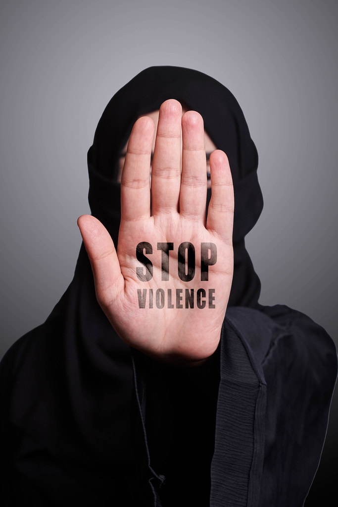 A muslim woman in traditional clothing showing stop handgesture with text - Stop violence