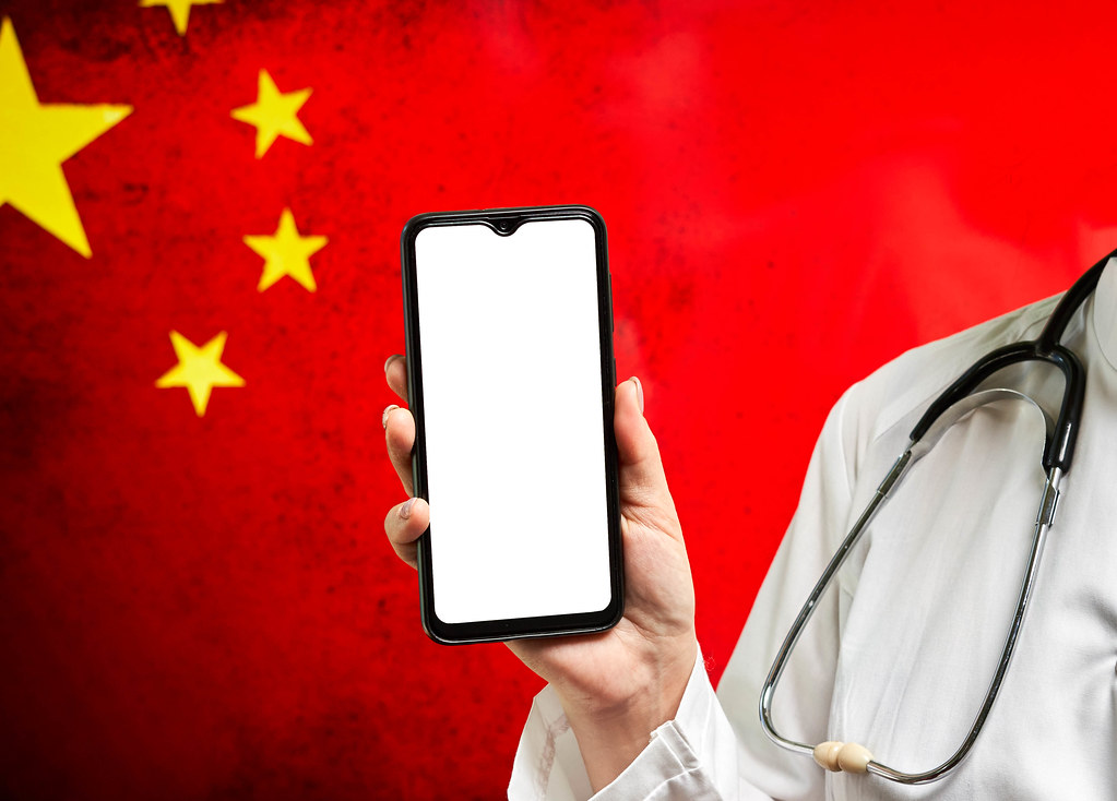 A nurse with a smartphone over Chinese flag