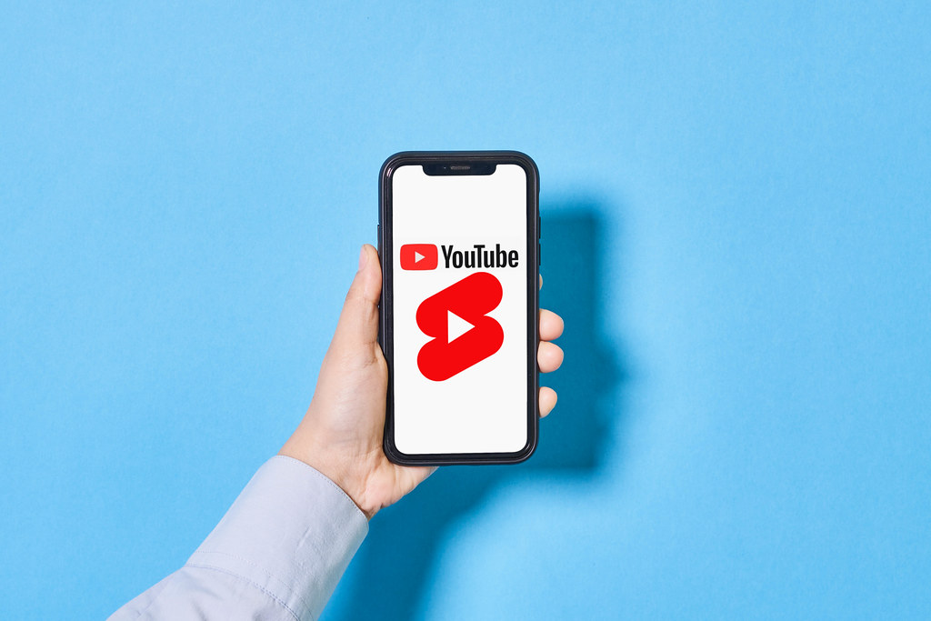 A person holds a smartphone with YouTube Shorts logo on screen