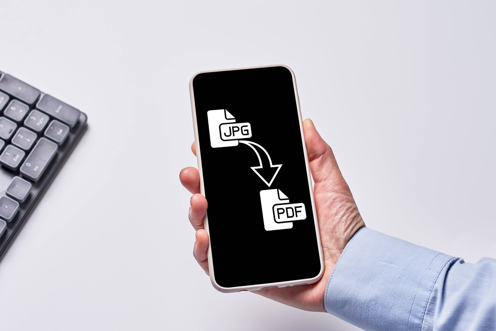 A person holds mobile phone with converting application - JPG to PDF