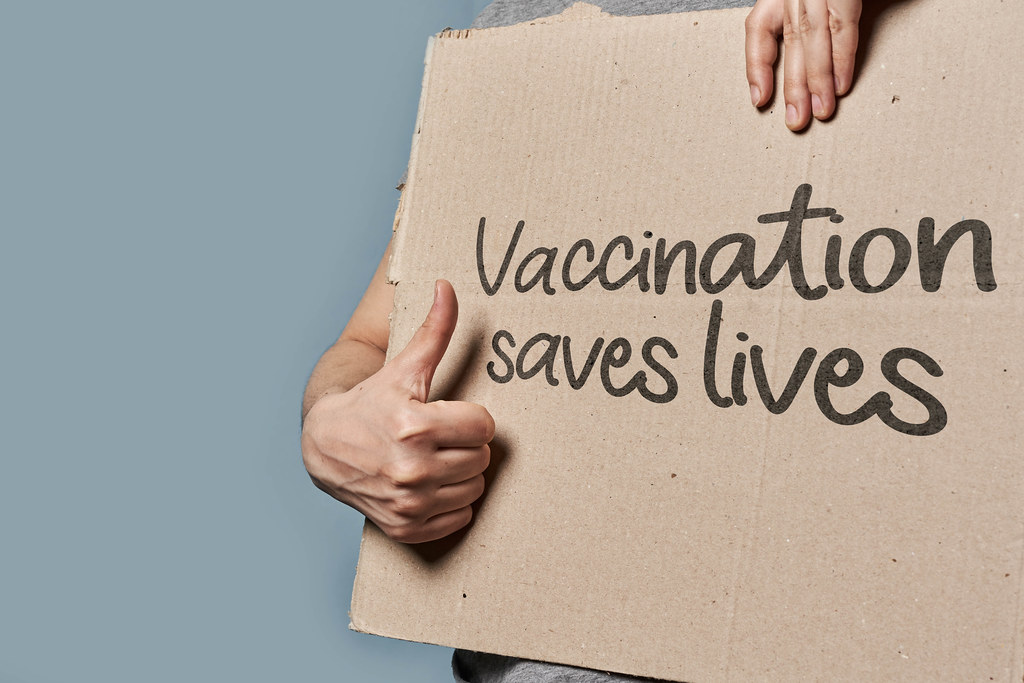 A person holds placard with text - Vaccination saves lives
