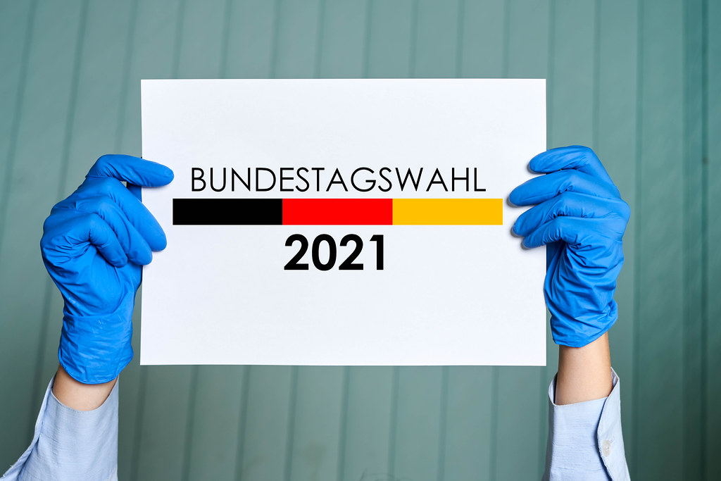 A person in medical gloves holds a placard with Bundestag elections symbol - Bundestagswahl 2021