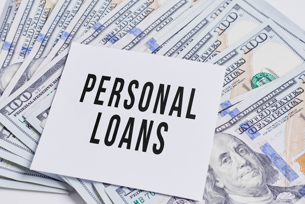 A pile of us dollars and a piece of paper with 'Personal loans' text