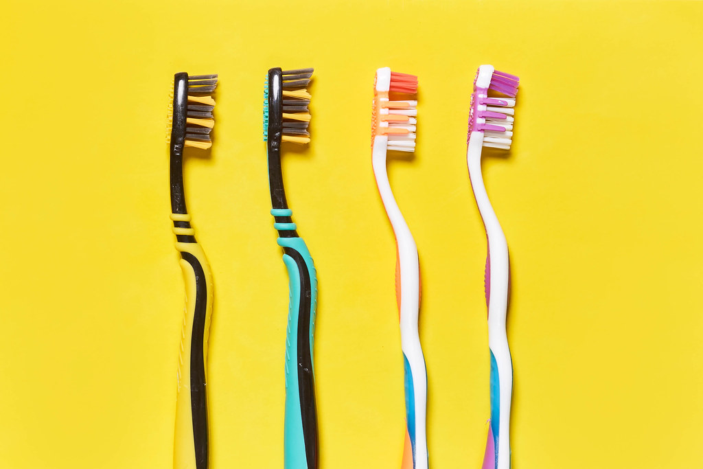 A row of toothbrushes on bright yellow background