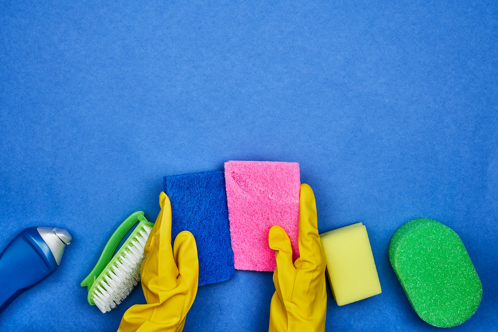 A rubber woman holds sponges over the cleaning products