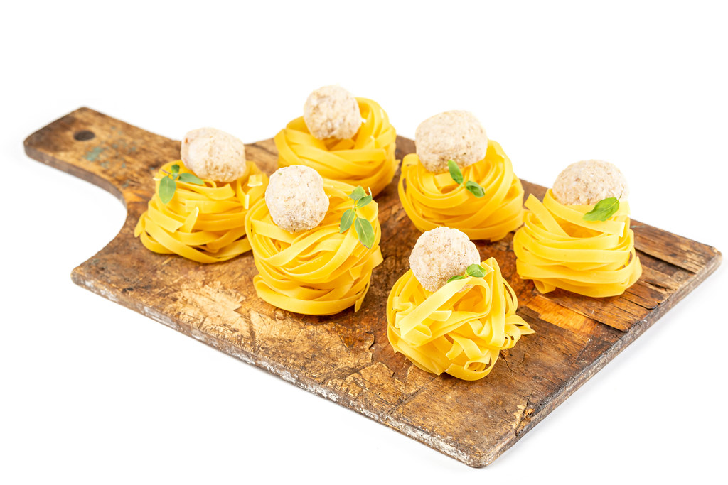 A set of raw fettuccine 6 pieces with meatballs and basil on an old wooden kitchen board