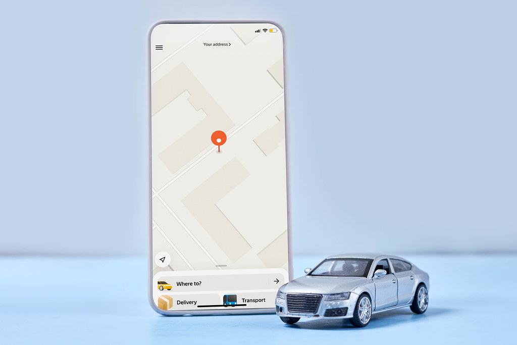 A smartphone with mobile taxi service application and car toy