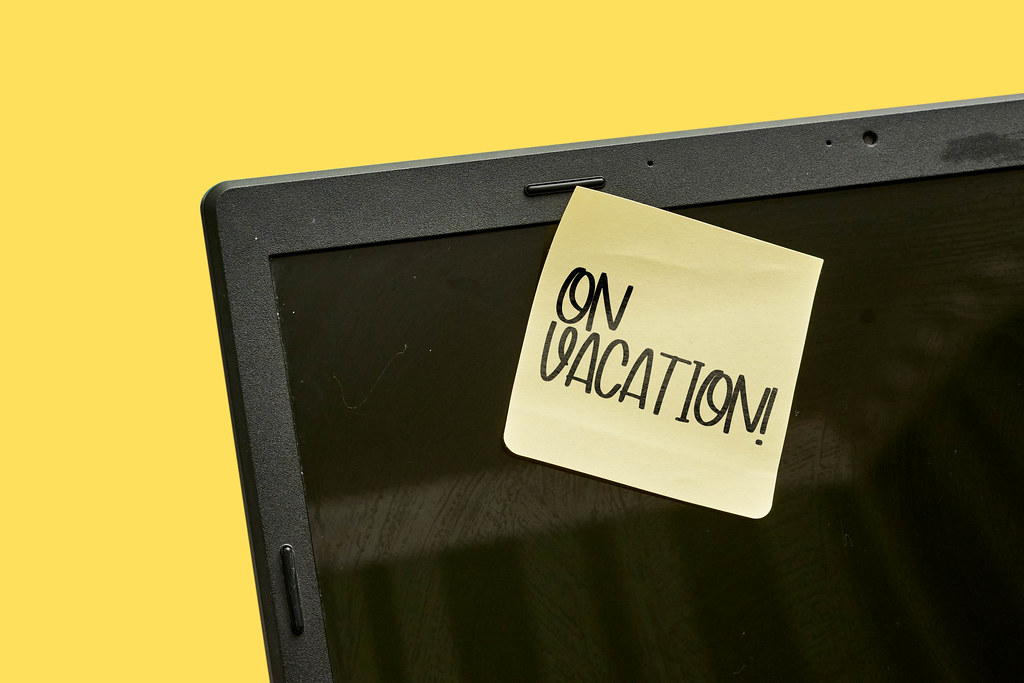 A sticky note on the laptop display with text - on vacation