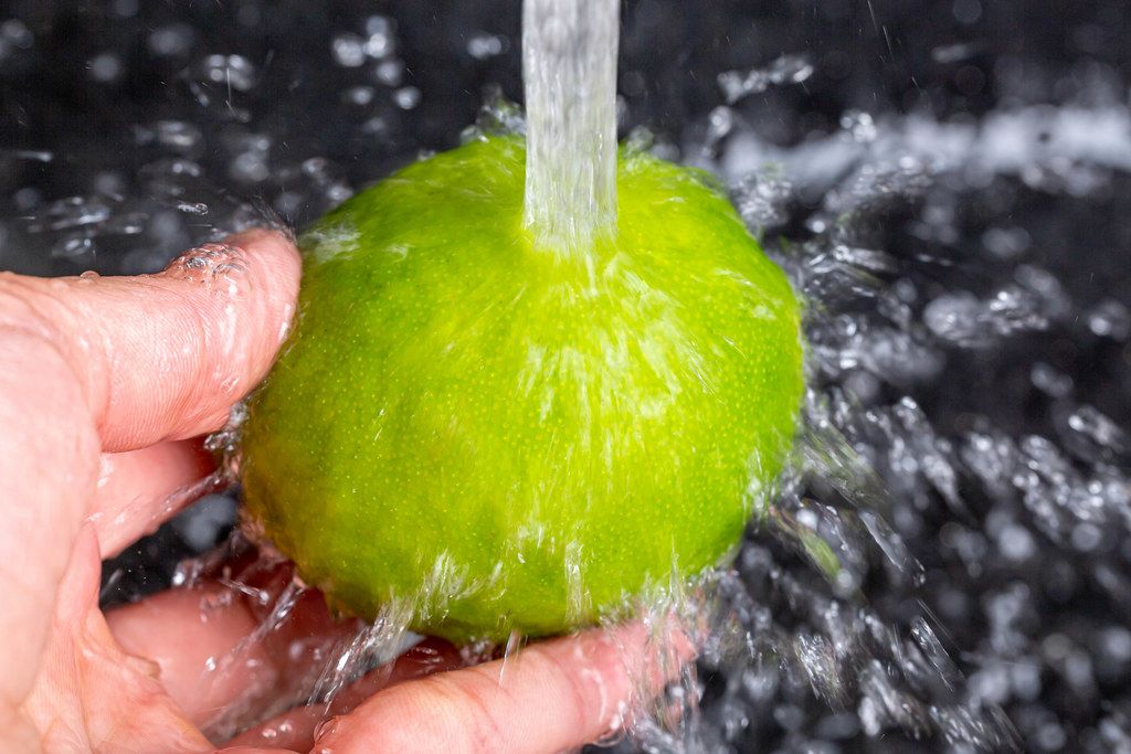 A stream of water pours onto fresh lime, close-up
