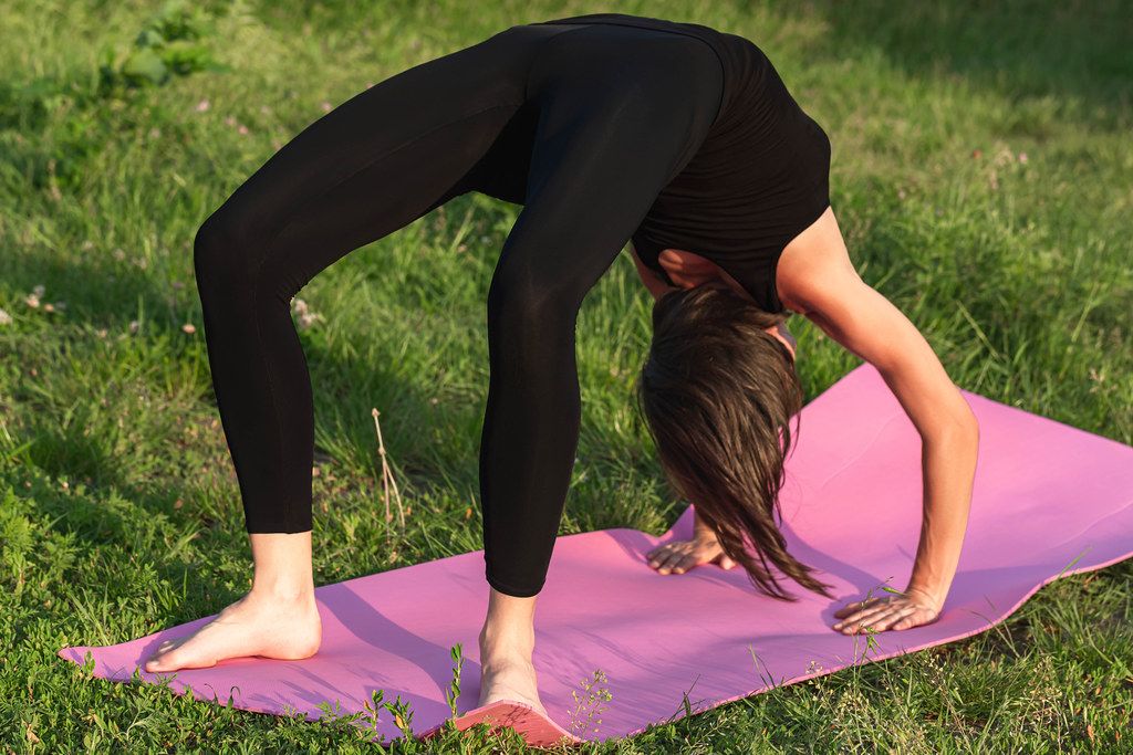 A woman performs the pose of Urdhwa Dhanurasana (bow down face)