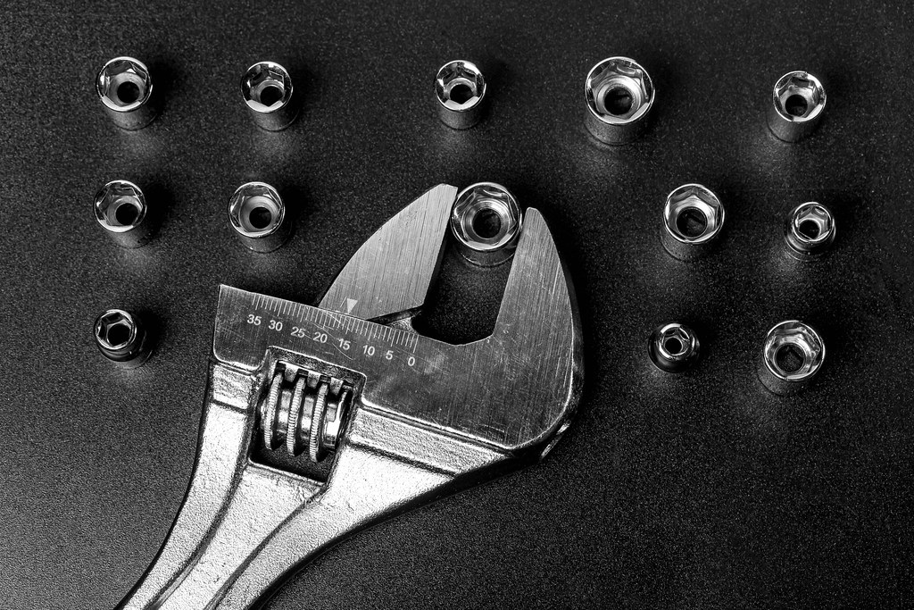 Adjustable wrench and screwdriver heads on black background