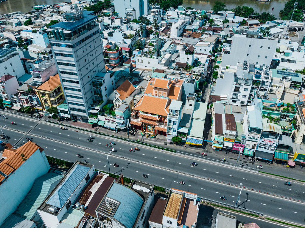 Aerial Drone Photo of a Buddhist Pagoda next to many Buildings along a Street with many Motorbikes in District 8 in Ho Chi Minh City, Vietnam
