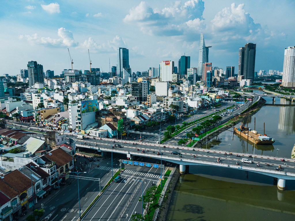 Aerial Drone Photo of Traffic on Ong Lanh Bridge with a Construction Boat on Saigon River and Bitexco Financial Tower in the Background in Ho Chi Minh City, Vietnam