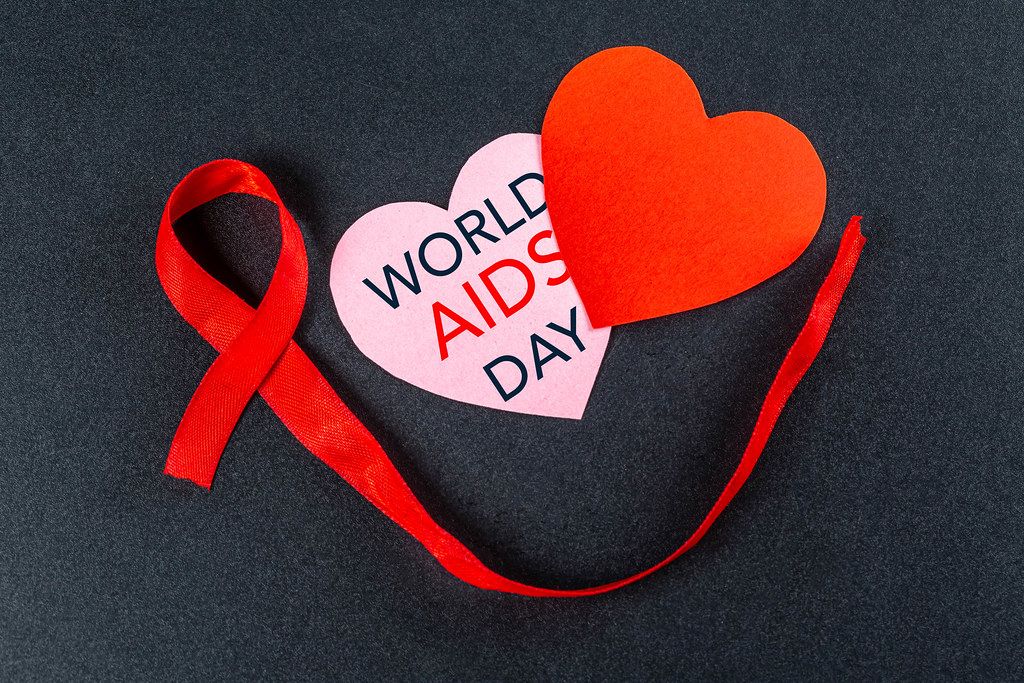 Aids day. Two hearts with red ribbon on a black background