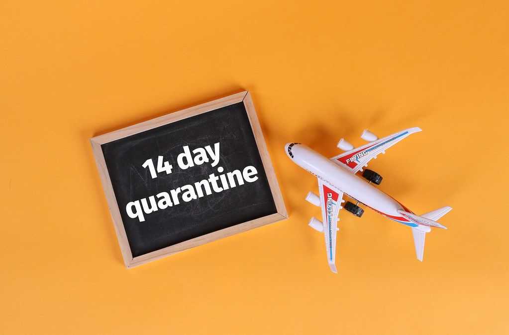 Airplane and blackboard with 14 day quarantine text on orange background