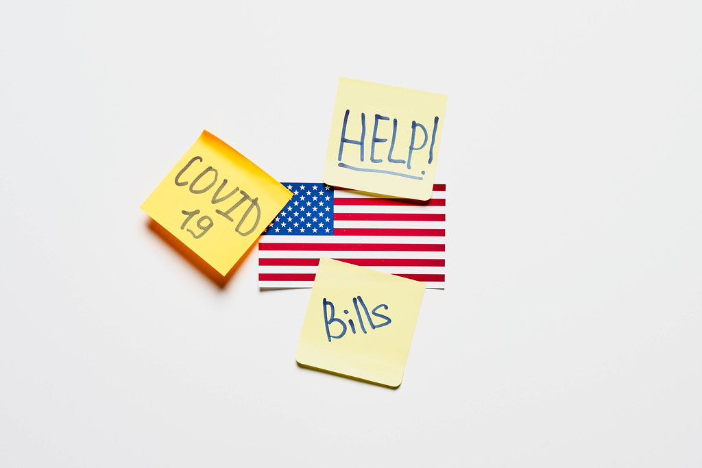 American flag and notes with Help, Covid-19 and bills texts