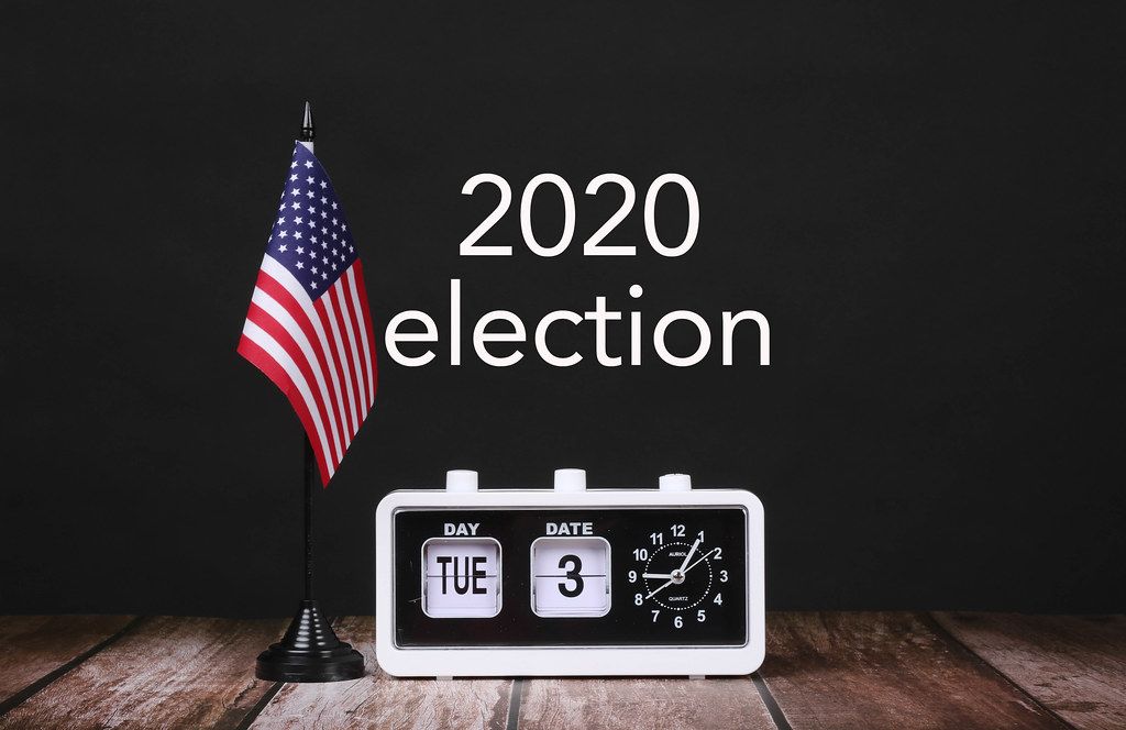 American flag and vintage clock with calendar showing 2020 election date