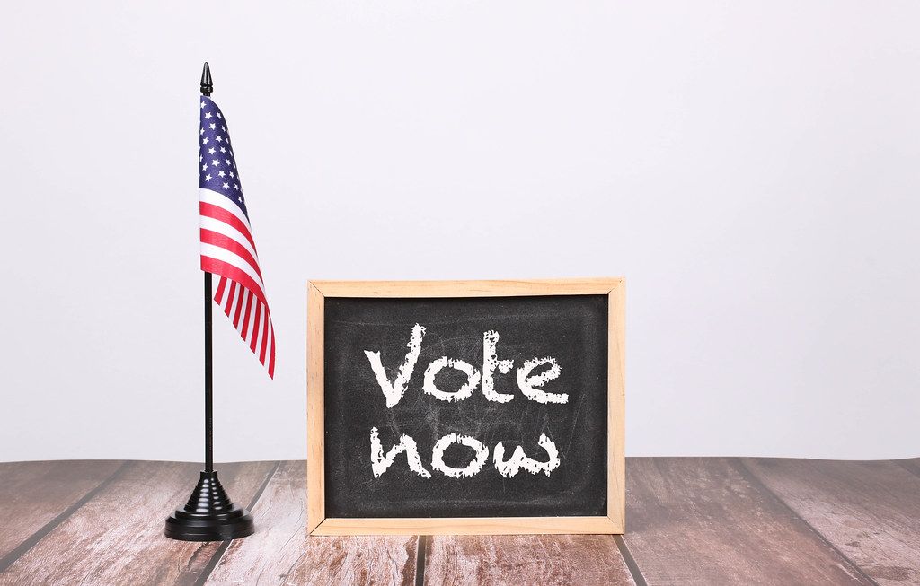 American flag with small blackboard and Vote now text