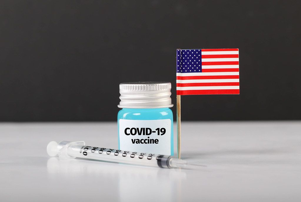 American flag with syringe and Covid-19 vaccine