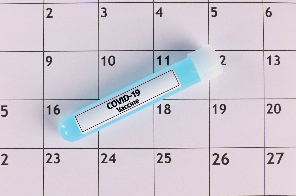 Ampule with Covid-19 vaccine on calendar