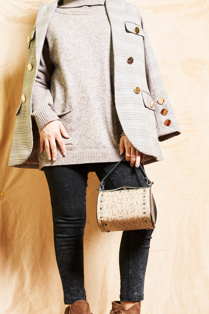 An unrecognizable model wearing a casual outfit holding handbag