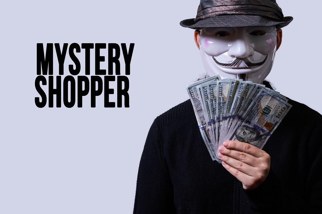 Anonymous person holds a pile of money. Mystery shopper