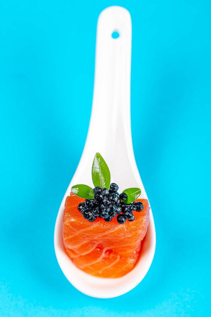 Appetizer of smoked salmon fillet and black caviar on a blue background