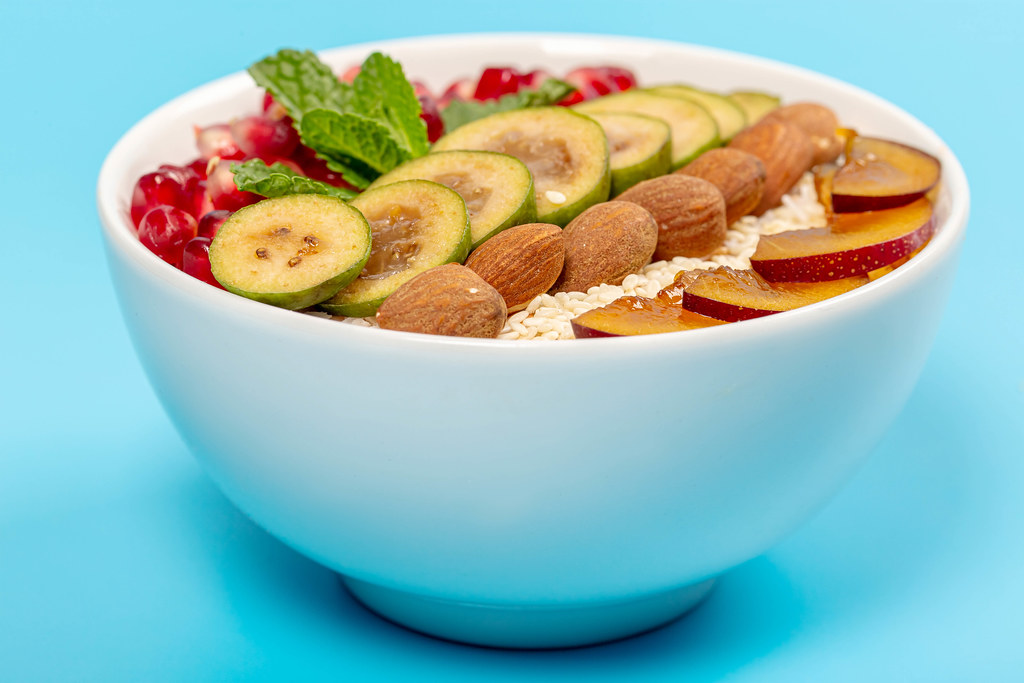 Appetizing oatmeal with fruits, almonds and mint on a blue background