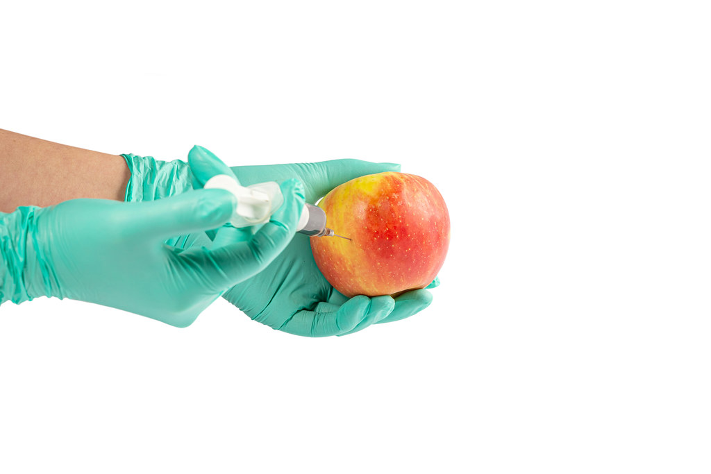 Apple in hand with rubber gloves and a syringe