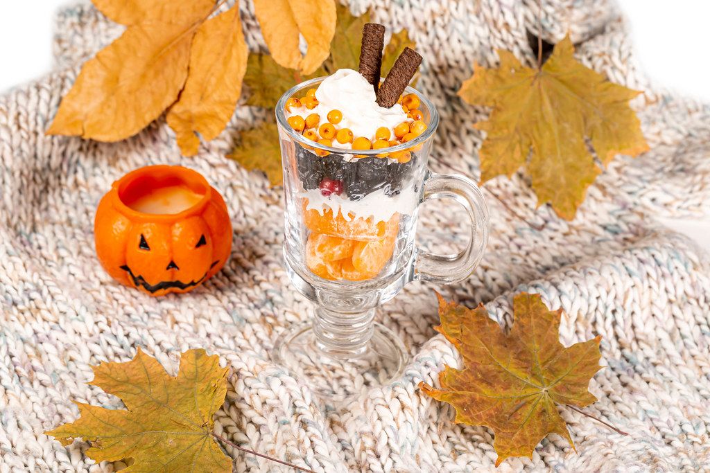 Autumn fruit dessert with pumpkin candles and dry leaves