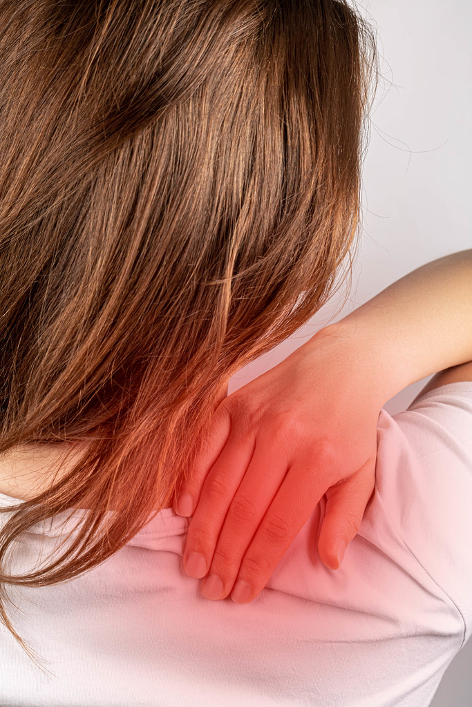 Back or shoulder pain concept, brunette woman massaging her shoulder
