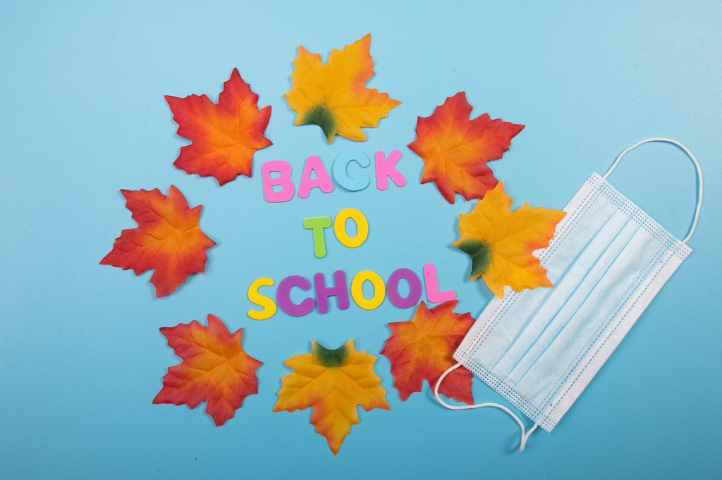Back to School text with autumn leaves and medical face mask