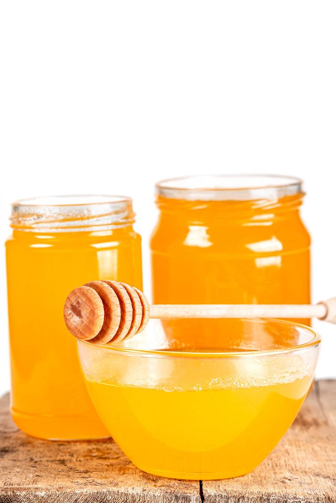 Background with natural bee honey in glass jars and a bowl