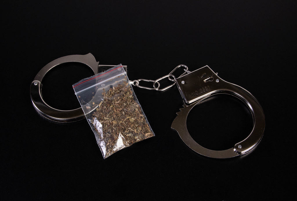 Bag of marijuana with handcuffs on black table