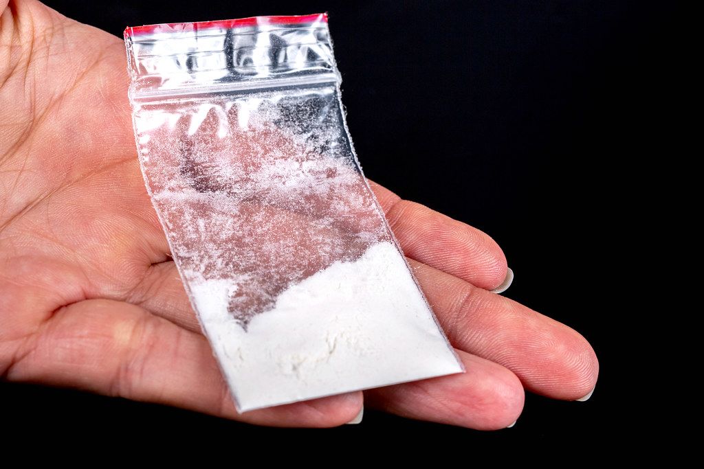 Bag with white powder in hand , close up. Illegal drugs