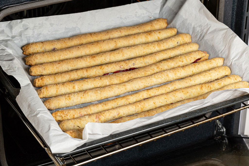 Baking tray in an open oven with baked cherry sticks