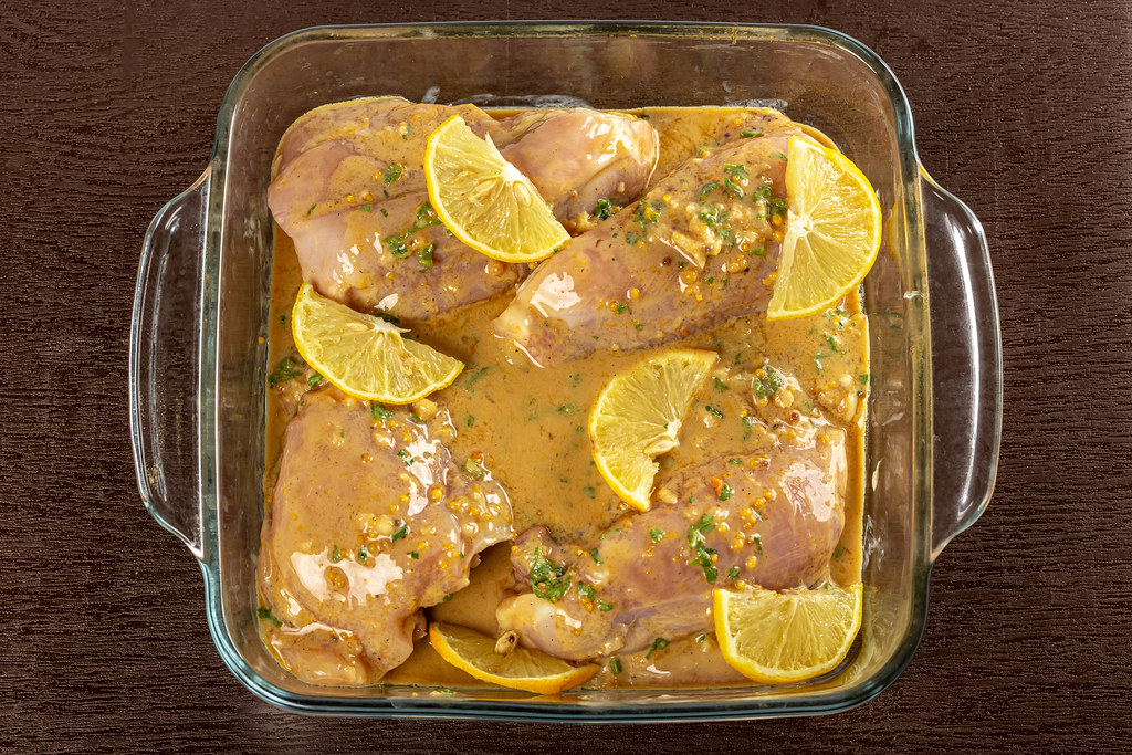 Baking tray with raw chicken and sauce for baking on brown
