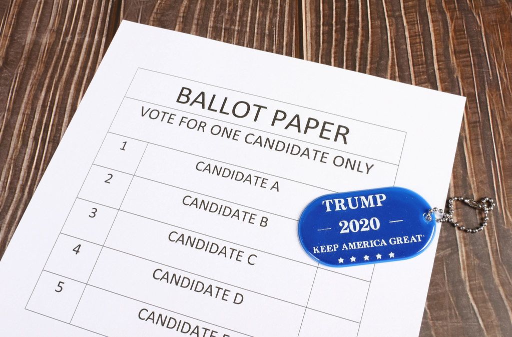 Ballot paper with blue military tag with Trump 2020 text on wooden table