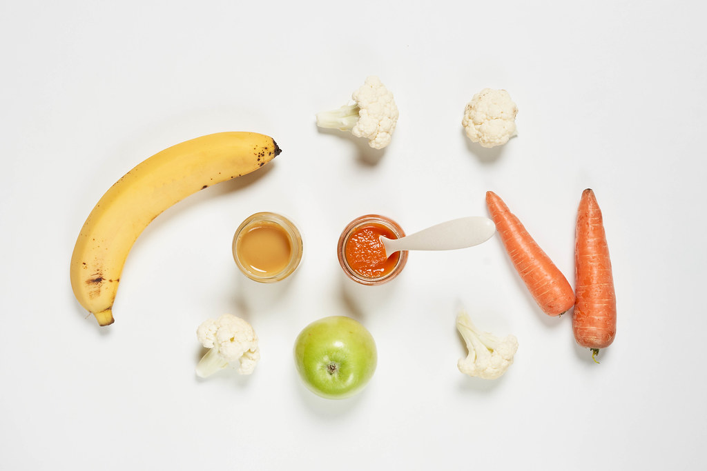 Banana and carrot-based purees with apple fruit and broccoli on white