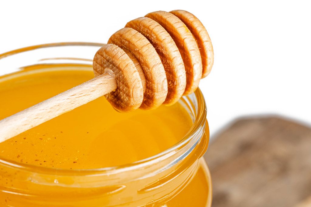 Bee honey in a jar with a honey dipper, close-up